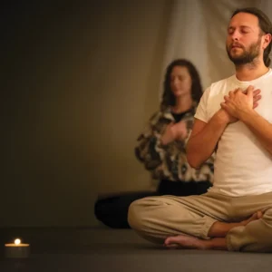 Two people seated on the floor, eyes closed, in meditation retreat