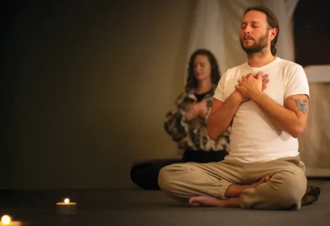 Two people seated on the floor, eyes closed, in meditation retreat