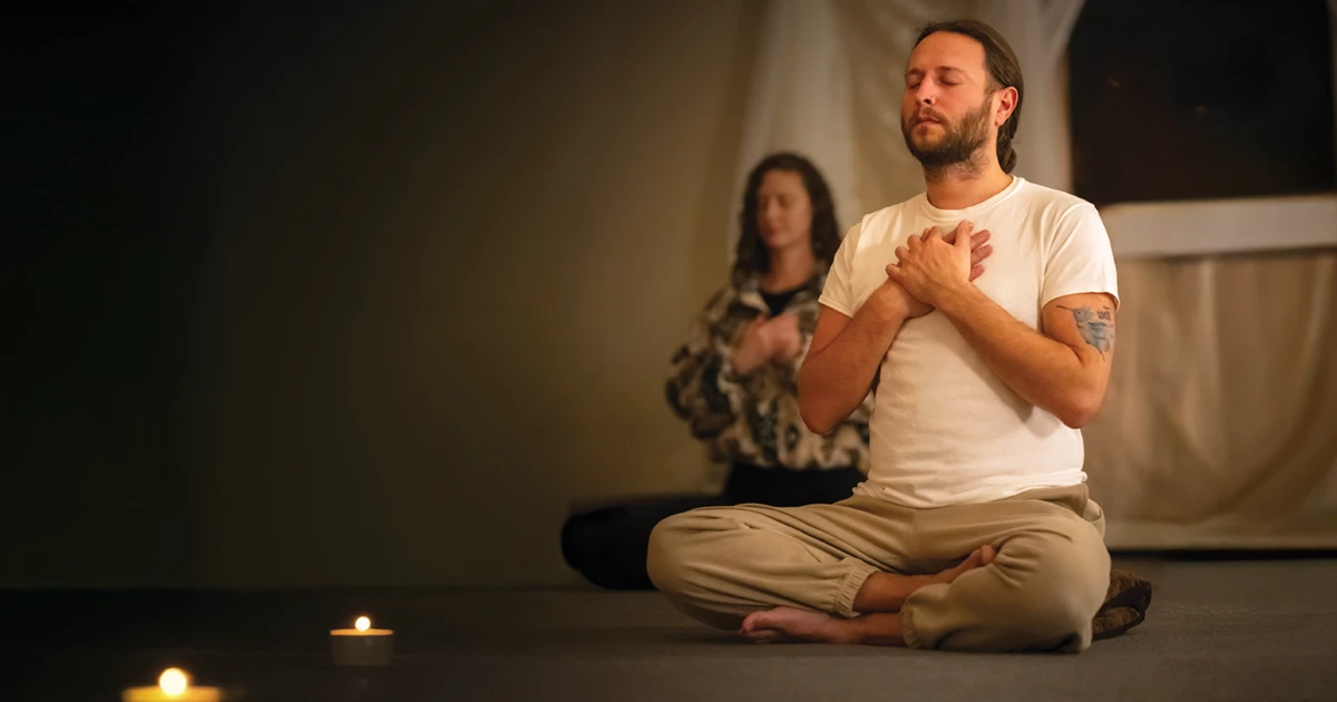 Two people seated on the floor, eyes closed, in meditation retreat