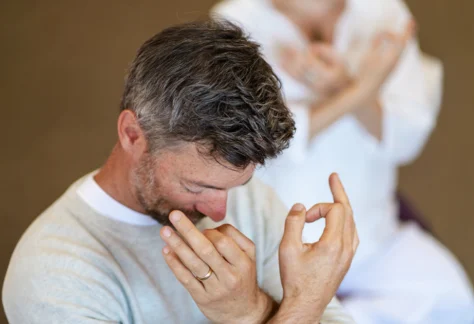 Person performing hand mudras with head bowed for Mount Madonna's New Year's Yoga Retreat in Northern California