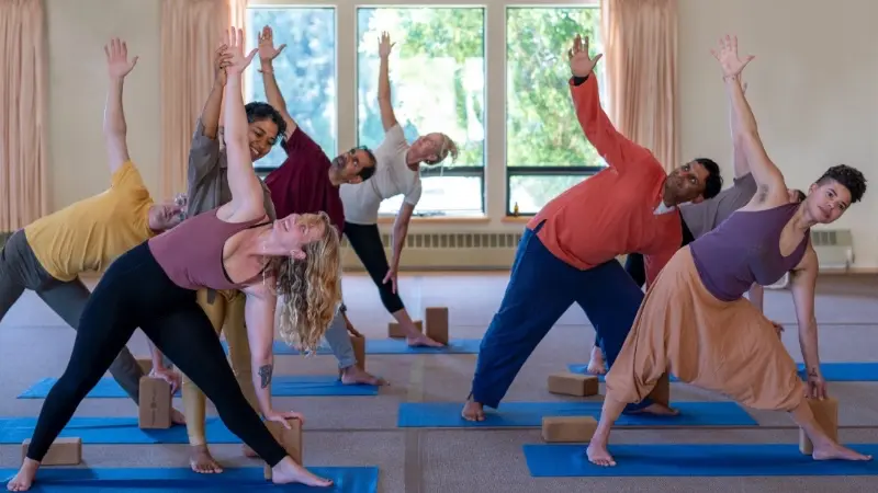 Yoga student practicing triangle pose with alignment support