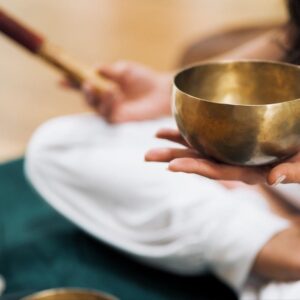 person holding Tibetan singing bowl leading yoga and sound healing class