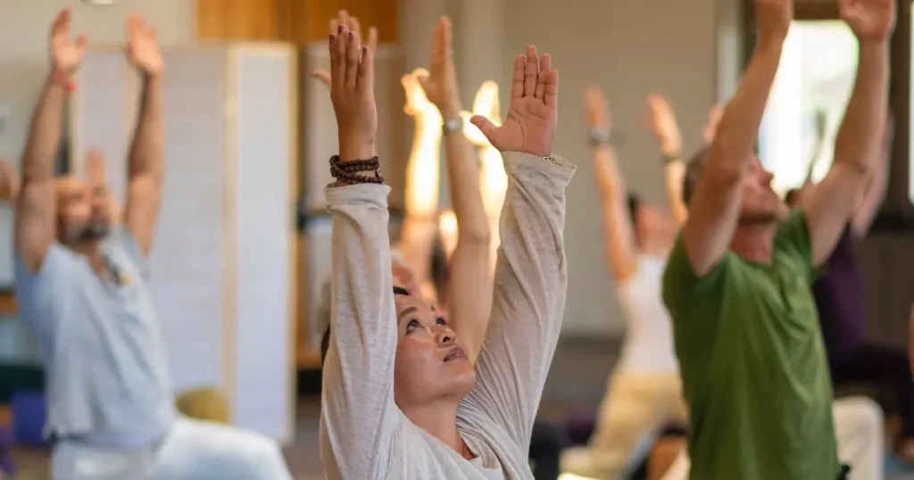 People with arms stretched upward in all-levels yoga class