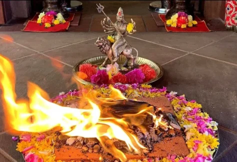 fire ceremony with flames in the center of flowers in front of a murti (statue)