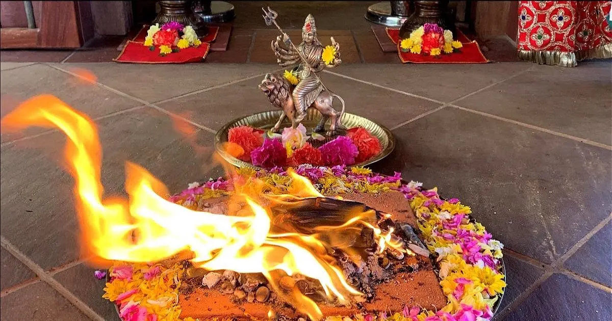 fire ceremony with flames in the center of flowers in front of a murti (statue)