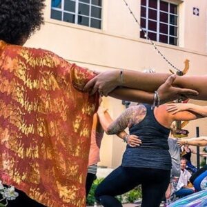 People gathered with arms outstretched and grasping each other for Yoga for All Movement Day
