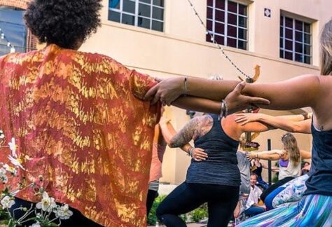 People gathered with arms outstretched and grasping each other for Yoga for All Movement Day