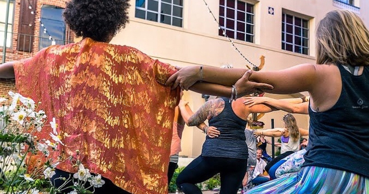 People gathered with arms outstretched and grasping each other for Yoga for All Movement Day