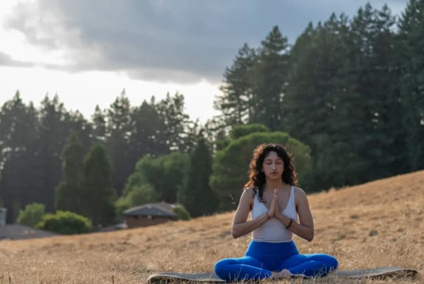 Person sitting in the grass in namaste, photo submitted for USA Today 10Best Awards: Best Yoga Retreat Center & Best Meditation Center
