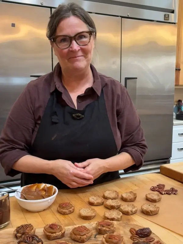 Christina, Resident Baker, smiling behind her mini pecan pies