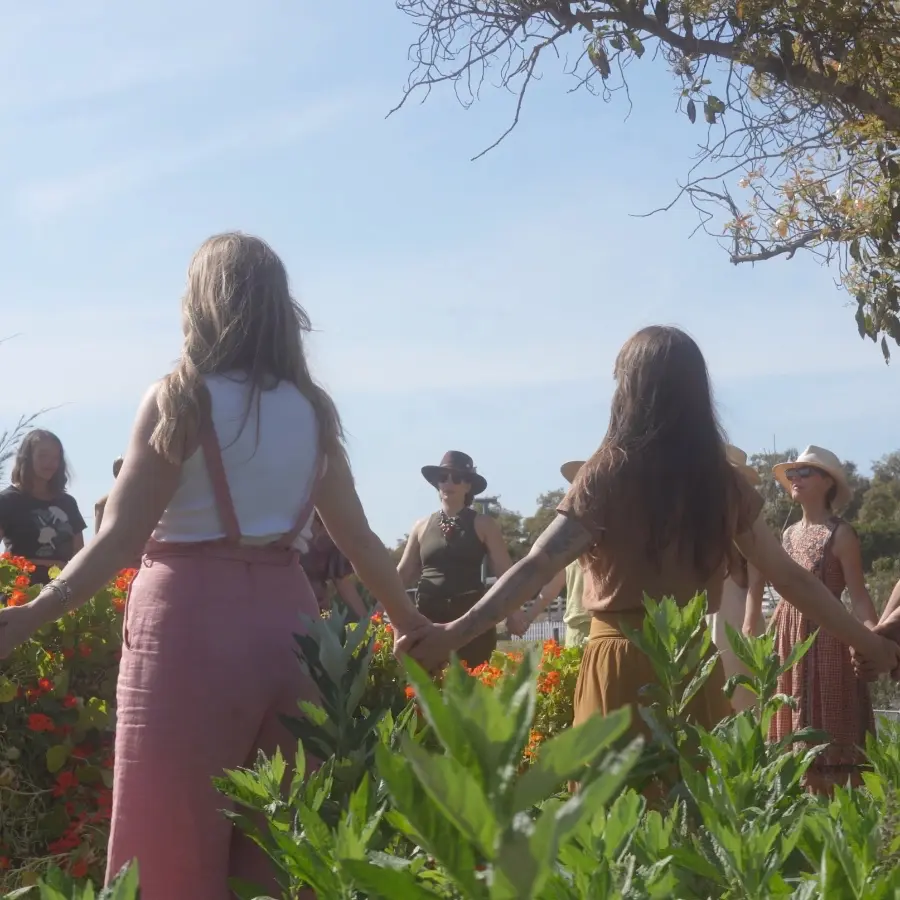 Circle of people holding hands for the School of the Sacred Wild Graduation Retreat 2026