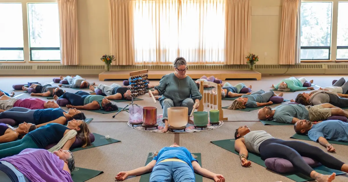 People in restorative yoga class experiencing sound immersion with crystal singing bowls