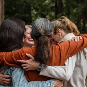 Group of people hugging outside in the redwood forest over Mother's Day Weekend