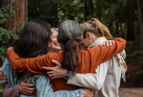 Group of people hugging outside in the redwood forest over Mother's Day Weekend