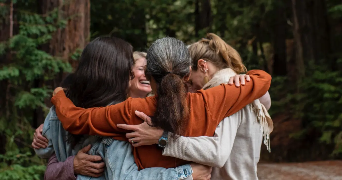 Group of people hugging outside in the redwood forest over Mother's Day Weekend