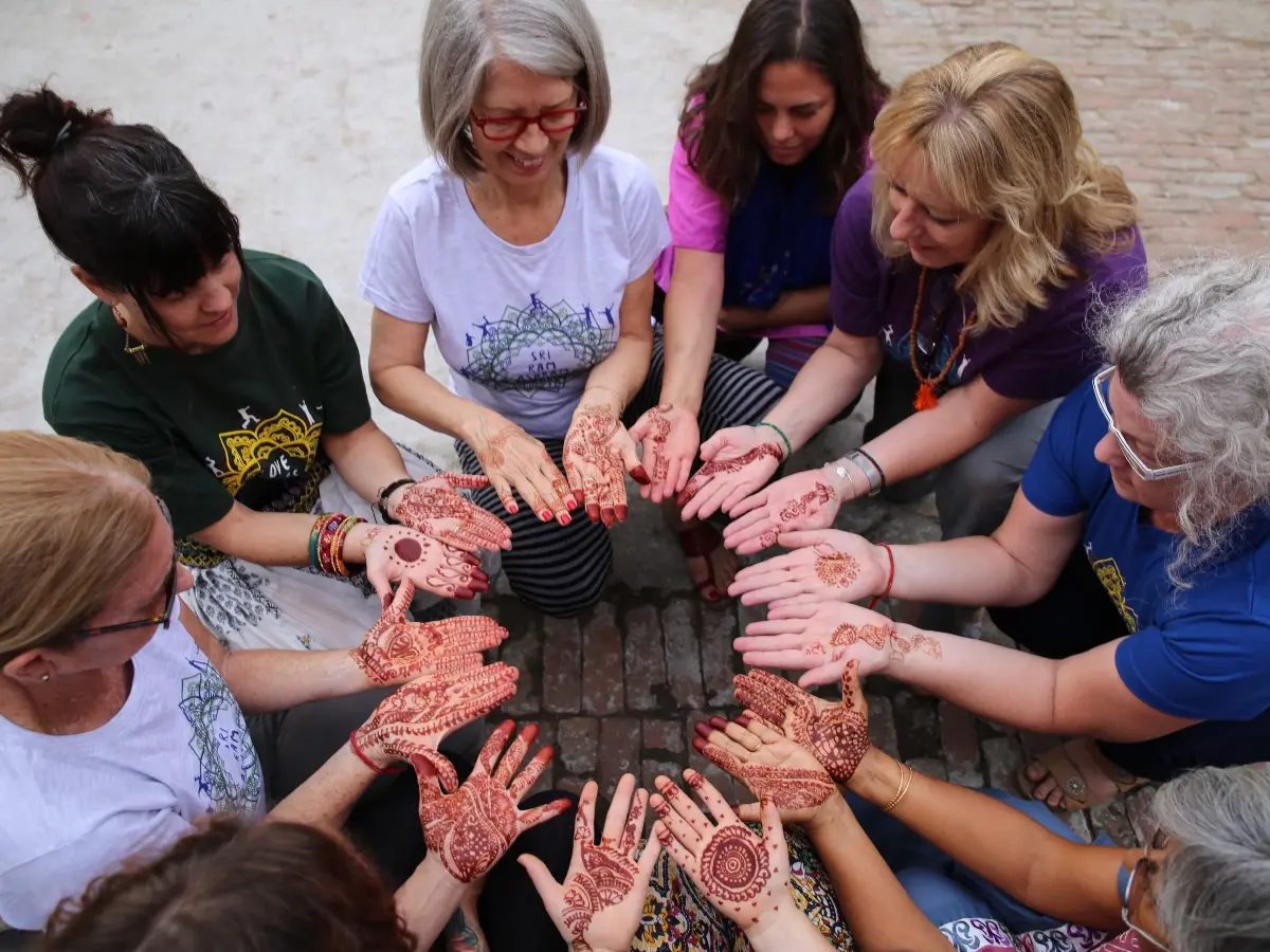 Group of participants of the Yoga Diwali India program standing in a circle with henna on their hands