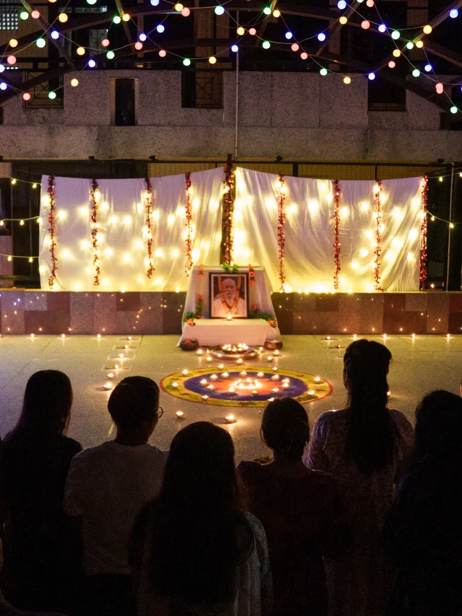 An altar with a picture of Baba Hari Dass surrounding by lights and people for Diwali at Sri Ram Ashram in Northern India