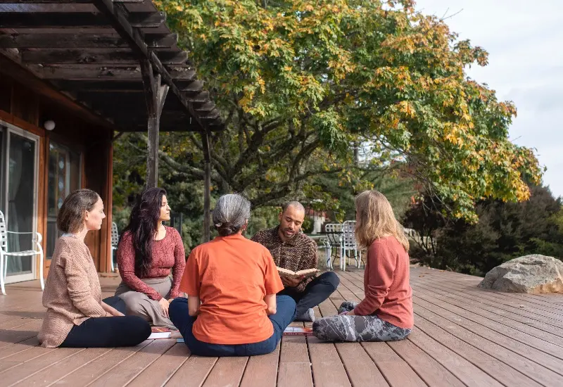 Small group of yoga students gathered with a faculty member on an outdoor deck at Mount Madonna, studying together in the Classical Ashtanga Yoga lineage