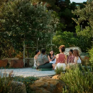 Circle of people in a garden for The Rooted Return retreat.