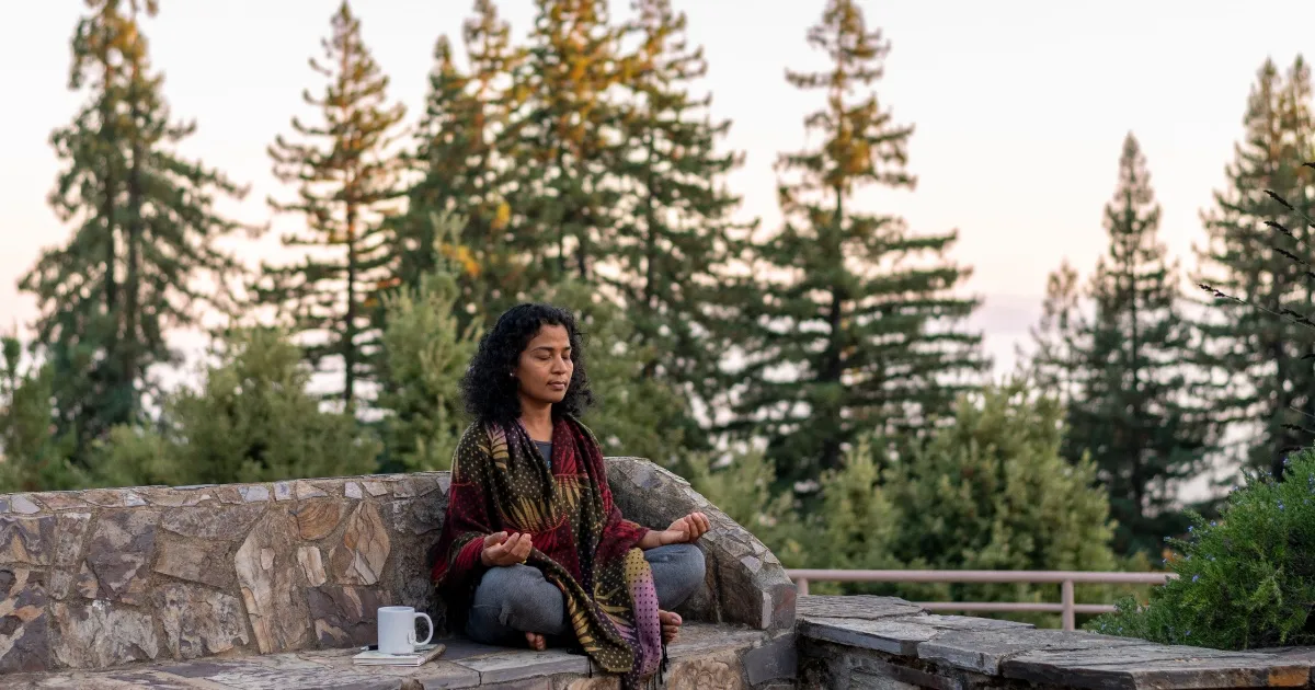 Person sitting outside among the redwood trees during the Fall Silent Meditation Retreat at Mount Madonna in Northern California