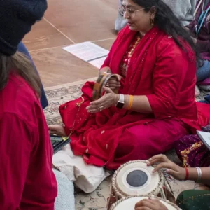 A group of people sitting at the Sankat Mochan Hanuman Temple singing kirtan and playing music, spending a weekend in community at Mount Madonna