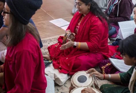 A group of people sitting at the Sankat Mochan Hanuman Temple singing kirtan and playing music, spending a weekend in community at Mount Madonna