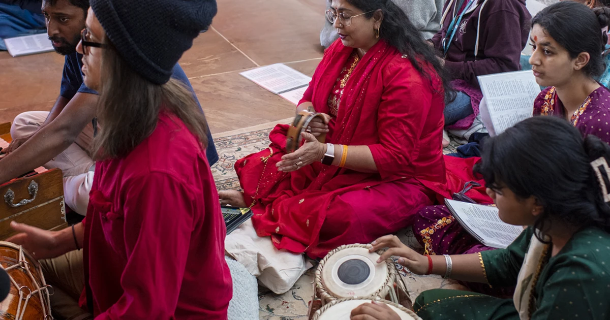 A group of people sitting at the Sankat Mochan Hanuman Temple singing kirtan and playing music, spending a weekend in community at Mount Madonna