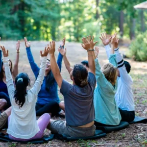 People sitting on the ground in a circle with arms outstretched for Hanuman Fellowship HFS Annual General Meeting at Mount Madonna